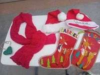 Full set on table: two stockings, two Santa hats, red scarf, green heart ornament