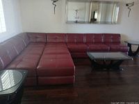 Full view of red leather sectional arranged in L-shape with ottoman in front
