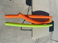 Two pool noodles, orange and green, on table