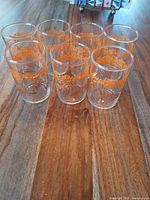 All seven glass tumblers displayed upright on wooden surface