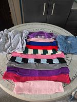 All 12 folded knit garments on table showing colour variety