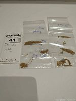 Group view of four bags containing gold chains, pendant, findings with lot weight tag visible