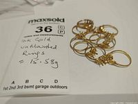 Group of unmounted gold ring settings with MaxSold lot tag showing 15.58 g
