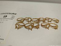 11 gold-plated filigree ring settings with MaxSold lot card visible