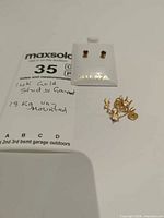 Carded 14K gold garnet stud earrings with loose settings displayed