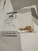 Clear bag containing multiple 14K gold earring findings with MaxSold lot tag showing weight 9.79 g