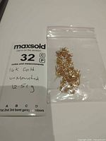 Bag of multiple 14K yellow gold earring findings on scale card