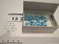 Box with loose blue topaz gemstones, reference label visible