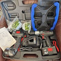 Drill, work light, two batteries, charger, blue stand, manuals inside molded carrying case