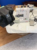 Full view of serger with foot pedal, bag, thread spools