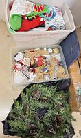 Bin containing assorted plastic ornaments, stockings, elf decoration and wrapping paper.