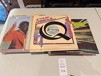Stack of LPs on table showing The Big Single Q, Love Unlimited, Freaker and others