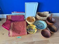 Group view of linens, ceramic pieces, wooden bowls with utensils, baskets and white tray