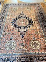 Full view of the rug showing peach field, navy medallion, geometric motifs and borders