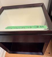 Angled view of one table showing mirrored top, wood frame, tape with dimensions