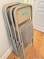 Four folded chairs stacked against wall showing frame color and upholstery