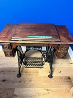 Full view of closed cabinet showing wood top, side drawers, iron base