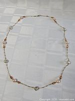 Full length view of necklace laid flat showing bead arrangement and chain