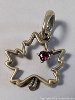 Front view of sterling silver maple leaf pendant with red heart stone and 925 stamp on bail