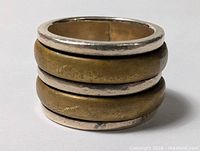 full view of ring showing three brass spinner bands and silver edges