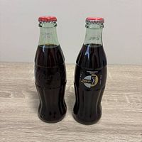 Front view of both sealed 8 fl oz contour bottles, showing embossed and printed variants