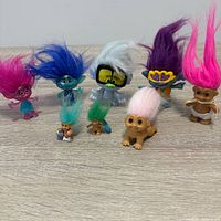 Seven troll mini figures arranged on tabletop displaying front view