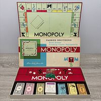 Open Monopoly box displaying board, money trays, cards, wooden houses and hotels