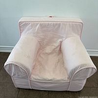 Front view of pink children's armchair showing overall design, color and wear