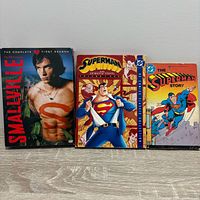 Front covers of Smallville S1 DVD, Superman Animated Series Vol.1 DVD, and The Superman Story book