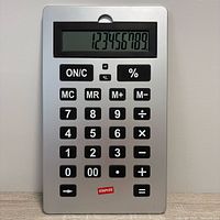 Front view showing silver face, large LCD displaying numbers, black oversized keys, Staples logo