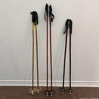Three pairs of bamboo ski poles standing against wall