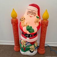 Front view of Santa blow mold flanked by two NOEL candles, cords visible