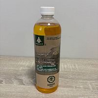 Front view of sealed Woods citronella lamp oil bottle