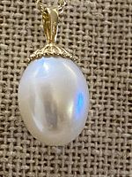 Close-up of baroque pearl pendant showing gold cap, bail, and lustre