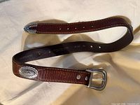 Full belt coiled showing buckle, concho and tip