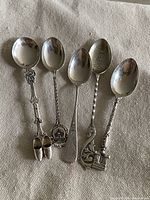 Front view of five sterling silver souvenir spoons