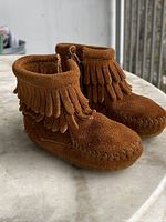 Overall view of both boots showing suede, fringe, moc toe stitching
