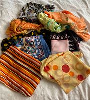 Pile of nine assorted scarves showing variety of colours and patterns