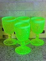 Four goblets glowing bright green under UV
