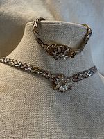 Necklace and bracelet displayed on bust form showing floral centers and tri-color links