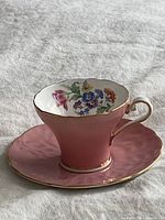 Teacup on saucer showing interior floral design and gold trim