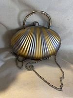 Front view showing gold and silver ribbed metal shell, top handle, chain strap