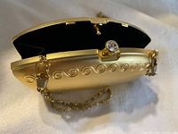 Open clutch showing black interior and jewel-topped clasp