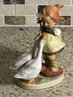 Front angled view of figurine showing girl, geese and colors