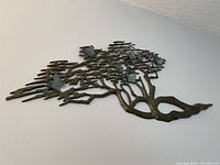 Angled view of entire brass tree wall sculpture mounted on wall