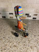 Left side view of tin wind-up duck riding tricycle
