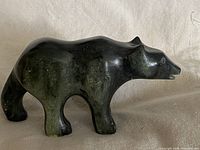 Profile view of dark green/black veined soapstone polar bear carving