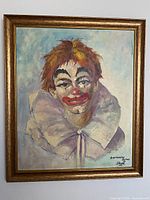 Framed oil painting of clown on wall