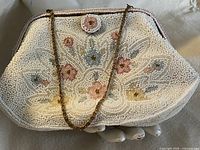 Front view of beaded clutch showing floral beadwork and chain strap