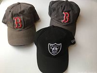 Front view of three caps showing team logos